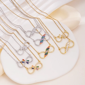 Elegant gold and silver infinity symbol necklaces with rainbow zircon on white tray