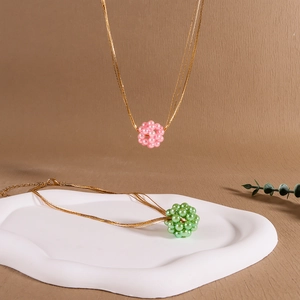Detailansicht handgefertigter Halsketten mit rosa und grünen Perlenanhängern in Kugelform