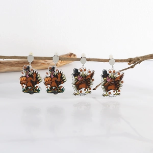 Detailed view of acrylic Thanksgiving turkey earrings hanging on a natural wooden branch