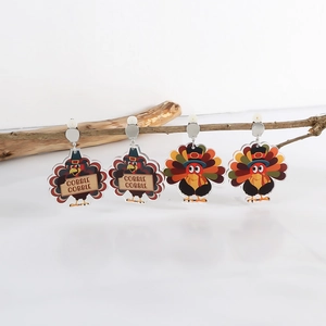 Detail of turkey-shaped acrylic earrings hanging on dry wood branch for Thanksgiving decoration