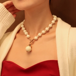 Détail du collier de perles blanches avec fermoir à bascule doré porté par un mannequin