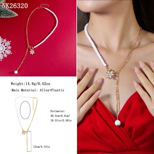Detailed specs of snowflake pendant necklace with white beads and gold chain on red background