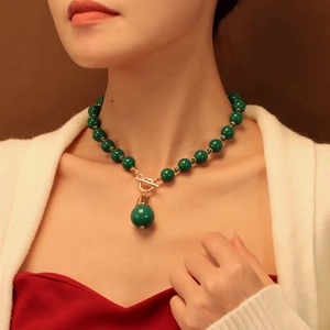 Détail d'un collier vintage avec de grandes perles vertes et fermoir doré type OT