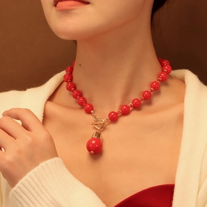 Détail d'un collier de perles rouges avec grand pendentif boule et fermoir OT doré
