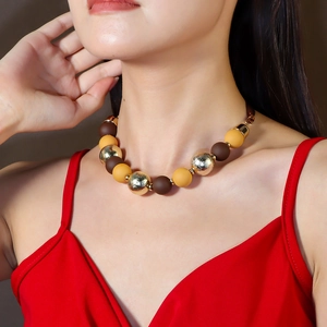 Colorful acrylic bead necklace with gold and matte beads worn by a model in red