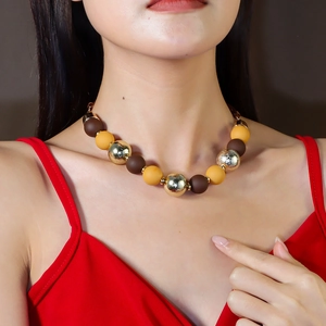 Detail of colorful acrylic beaded necklace with gold and matte beads worn by a model