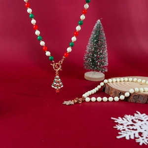 Weihnachtsperlenkette mit Emaille-Baum und Schneeflockenanhänger auf festlichem Grund
