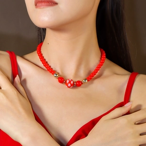 Détail de collier perles rouges avec perle flocon de neige et séparateurs dorés