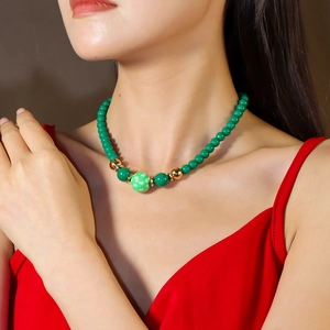 Gros plan d'un collier de perles sur modèle avec motif sapin de Noël et perles dorées