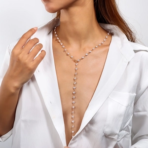 Dettaglio della collana lunga a Y dorata con perle a cuore indossata dalla modella