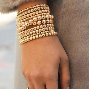 Stacked 4/5/6mm gold bead bracelet set on a grey plush display for a minimalist look