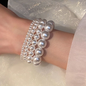 Detailed view of elastic pearl bracelets in various sizes on an elegant fabric background