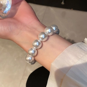 Detailed view of 12mm white pearl elastic bracelet worn on wrist for scale