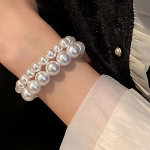 Elegant double-layered white pearl bracelet with varied bead sizes on a female wrist