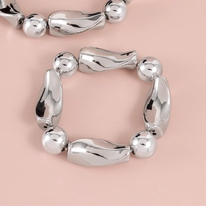 Makroaufnahme vom silbernen Liquid-Metal-Armband mit polierten runden und unregelmäßigen Perlen