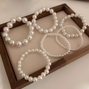 Elegant elastic pearl bracelets in various sizes on a rustic wooden display tray