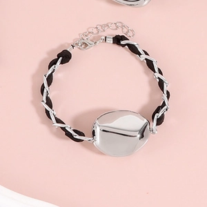 Detail von Silberkette und schwarzem Seilarmband mit großer geometrischer Metallplatte