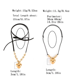 Deux colliers avec pendentif cœur, cordons noirs et perles dorées polies sur fond blanc