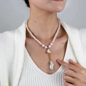 Gros plan d'un collier de perles avec pendentif papillon et glands en perles baroques