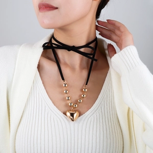 Détail d'un collier choker noir réglable avec perles dorées et grand pendentif en cœur