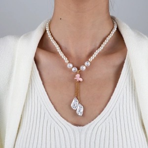 Détail d'un collier de perles avec pendentif papillon rose et perles baroques