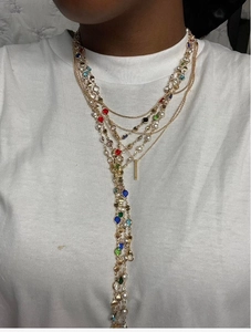 Dettaglio della collana a frange dorate multistrato con cristalli colorati su maglia