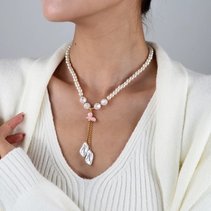 Détail d'un collier de perles avec pendentif papillon rose et perles baroques sur mannequin