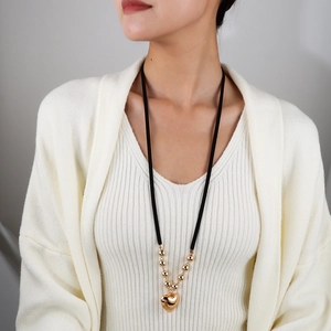 Détail d'un collier avec pendentif cœur doré et perles sur cordon ajustable
