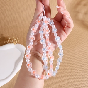 Handmade beaded phone strap with white pearls and colorful acrylic floral charms on a wrist cord
