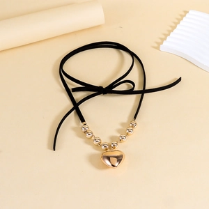 Détail du pendentif cœur doré avec perles lisses sur un collier en cordon noir stylé