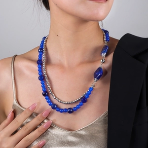 Detail einer doppellagigen Perlenkette mit königsblauen Anhängern an einem Model