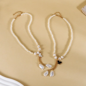 Vue macro des pendentifs papillon et perles baroques sur d'élégants colliers dorés