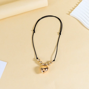 Détail du collier ajustable en cordon noir avec pendentif cœur doré et perles décoratives