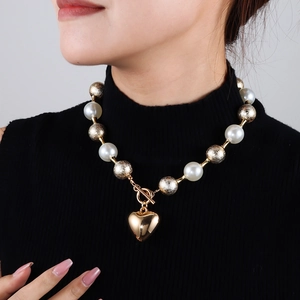 Vue détaillée du collier en perles punk avec grand pendentif cœur doré et fermoir en T