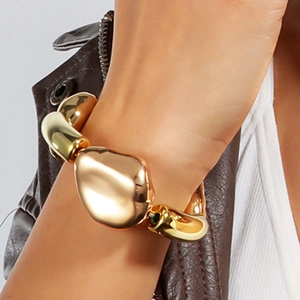 Detail eines klobigen goldenen Armbands mit Lederjacke kombiniert für einen modernen Look
