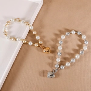 Détail de pendentifs cœur en or et argent avec perles mates et perles blanches