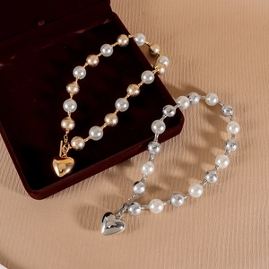 Détail de bracelets en perles avec billes métalliques texturées et breloques coeur fermoir OT