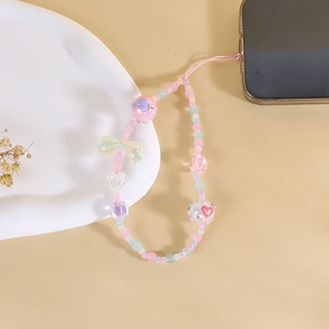 Colorful beaded phone strap with macaron hearts and bow on a warm background