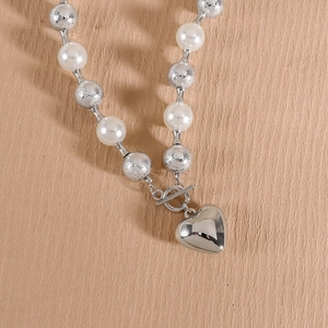 Détail macro du collier cœur avec perles, billes argentées et fermoir à bascule chic