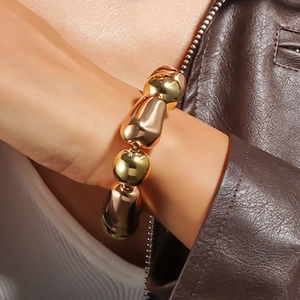 Details eines klobigen Stretch-Armbands mit polierten Perlen in Gold und Roségold