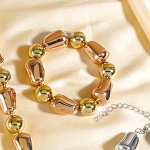 Nahaufnahme von goldenen und silbernen Perlenarmbändern und Halskette auf Satinhintergrund