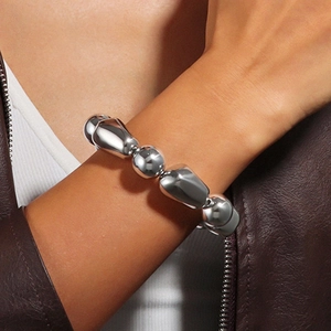 Detail eines silbernen Armbands mit organischen Perlen und hochglanzpolierter Oberfläche