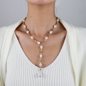 Primer plano de collar en Y con perlas barrocas y eslabones dorados estilo bambú en modelo