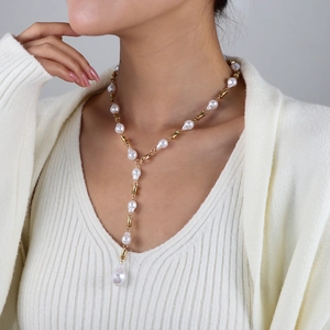 Elegante collar en forma de Y con perlas barrocas blancas y eslabones dorados en una modelo