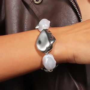 Detail eines klobigen Silbermetall- und Perlenarmbands, kombiniert mit einer Lederjacke
