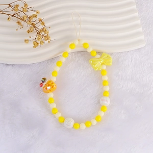 Close-up of yellow strawberry cake phone strap with sweet beads and shiny bow charm