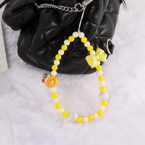 Sweet yellow strawberry cake beaded phone charm with bow on a black quilted bag