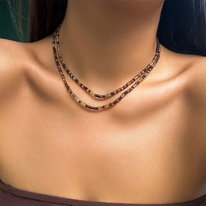 Detail van een dubbellaagse kralenketting in amber en bruin op het sleutelbeen