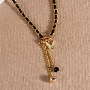 Detail of velvet chain necklace featuring a butterfly pendant and elegant tassel charms