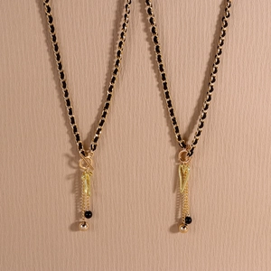 Close-up of heart charm and gold metal spheres on velvet woven fringe necklace